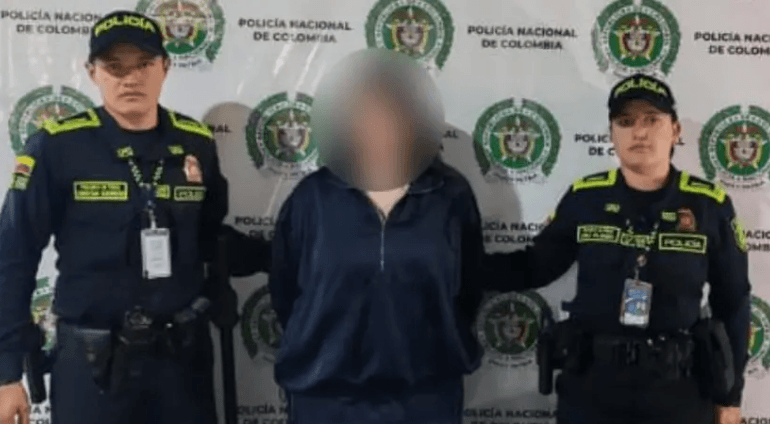 Mujer esposada es custodiada por dos agentes de la Policía Nacional junto a una patrulla en una zona rural con vegetación